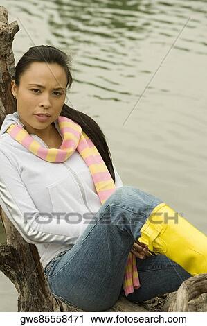 Portrait of a young woman sitting on a tree trunk by the lake View Large Photo Image Stock Image - Portrait of a young woman sitting on a tree trunk by the lake. Fotosearch