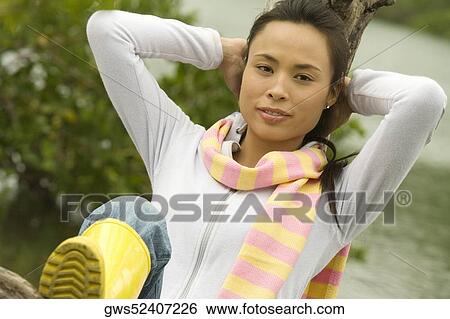 Portrait of a young woman sitting on a tree trunk by the lake View Large Photo Image Stock Photograph - Portrait of a young woman sitting on a tree trunk by the lake. Fotosearch