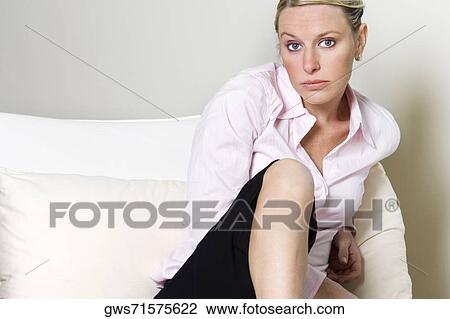 Stock Image - Portrait of a young woman sitting on the bed. Fotosearch