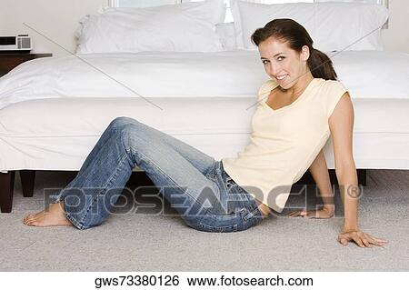 Stock Photograph - Portrait of a young woman sitting on the floor. Fotosearch