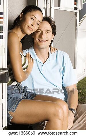 Stock Photo - Portrait of a young woman sitting with her arm around a mid adult man. Fotosearch