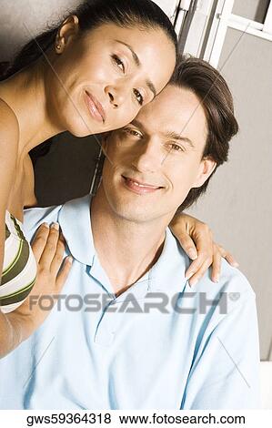 Stock Photo - Portrait of a young woman sitting with her arm around a mid adult man. Fotosearch