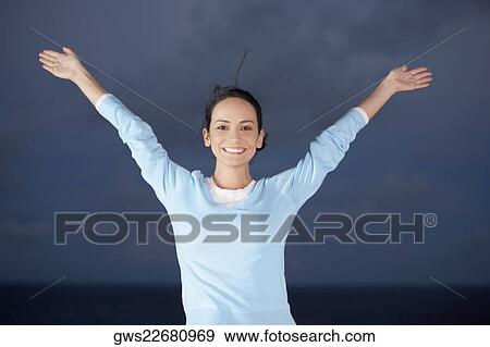 Portrait of a young woman smiling with her arms raised View Large Photo Image Stock Photo - Portrait of a young woman smiling with her arms raised. Fotosearch