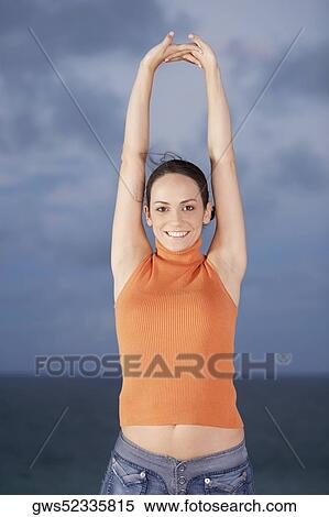 Portrait of a young woman standing with her arms raised View Large Photo Image Stock Photography - Portrait of a young woman standing with her arms raised. Fotosearch