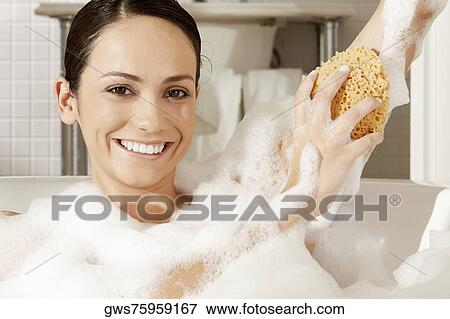 Portrait of a young woman using a bath sponge on her arm View Large Photo Image Stock Photo - Portrait of a young woman using a bath sponge on her arm. Fotosearch