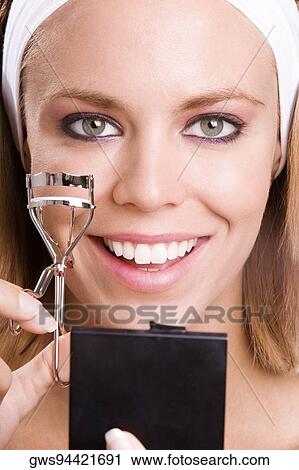 Portrait of a young woman using a eyelash curler View Large Photo Image Stock Image - Portrait of a young woman using a eyelash curler. Fotosearch