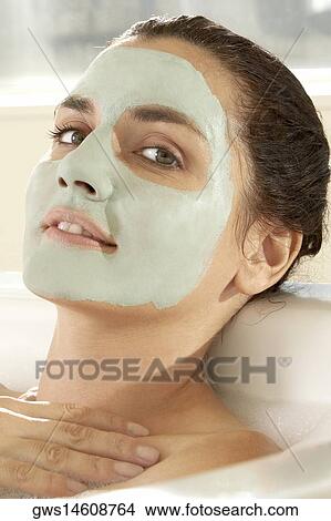 Portrait of a young woman wearing a facial mask in a bathtub View Large Photo Image Picture - Portrait of a young woman wearing a facial mask in a bathtub. Fotosearch