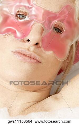 Portrait of a young woman wearing an eye mask in a bathtub View Large Photo Image Picture - Portrait of a young woman wearing an eye mask in a bathtub. Fotosearch