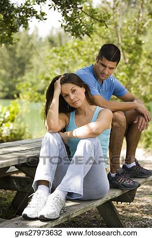 Stock Image - Portrait of a young woman with a mid adult man looking at her. Fotosearch