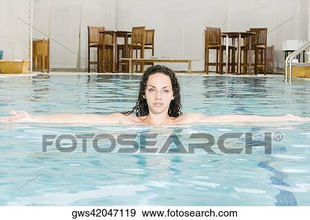 Stock Photo - Portrait of a young woman with her arms outstretched in a swimming pool. Fotosearch