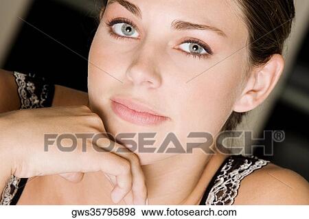 Stock Photo - Portrait of a young woman with her hand on her chin. Fotosearch