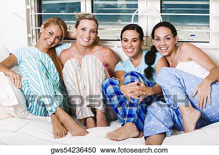 Stock Image - Portrait of four young women smiling on a couch. Fotosearch