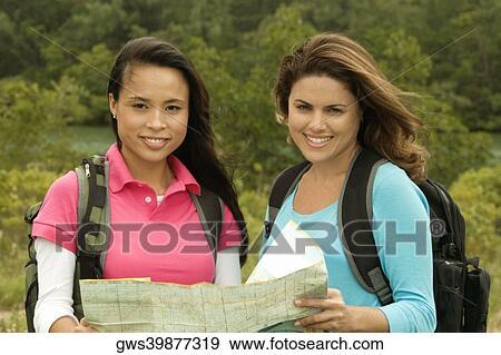 Portrait of two young women holding a map smiling View Large Photo Image Stock Photo - Portrait of two young women holding a map smiling. Fotosearch