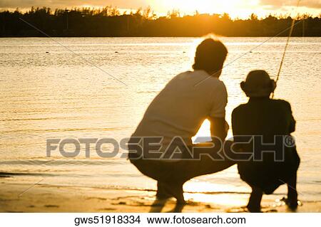 Picture - Rear view of a father and his son fishing. Fotosearch