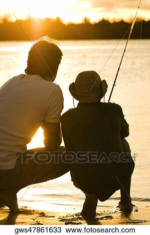 Rear view of a father and his son fishing View Large Photo Image Stock Image - Rear view of a father and his son fishing. Fotosearch