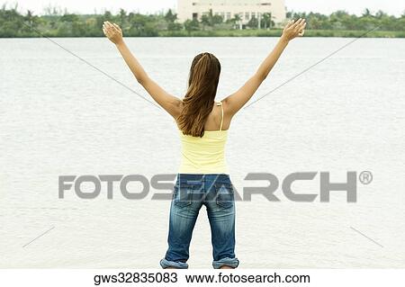 Rear view of a girl standing in water with her arms outstretched View Large Photo Image Stock Image - Rear view of a girl standing in water with her arms outstretched. Fotosearch