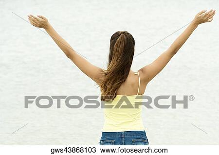 Rear view of a girl standing in water with her arms outstretched View Large Photo Image Stock Image - Rear view of a girl standing in water with her arms outstretched. Fotosearch