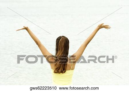 Rear view of a girl standing on the beach with her arms outstretched View Large Photo Image Stock Image - Rear view of a girl standing on the beach with her arms outstretched. Fotosearch