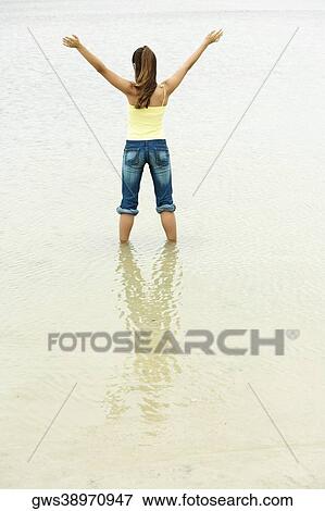 Rear view of a girl standing on the beach with her arms outstretched View Large Photo Image Stock Photo - Rear view of a girl standing on the beach with her arms outstretched. Fotosearch
