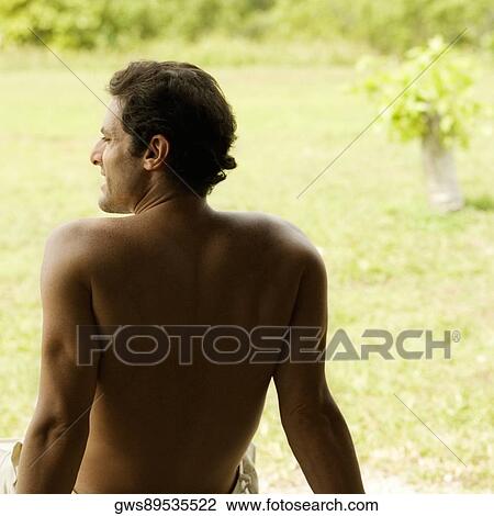 Stock Image - Rear view of a mid adult man sitting on a bench. Fotosearch
