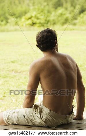 Stock Photo - Rear view of a mid adult man sitting on a bench. Fotosearch