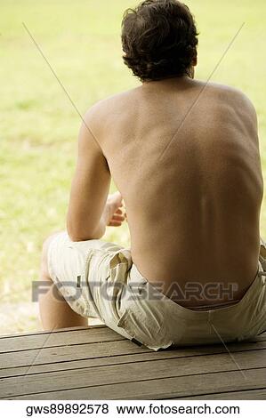 Rear view of a mid adult man sitting on a bench View Large Photo Image Stock Photo - Rear view of a mid adult man sitting on a bench. Fotosearch