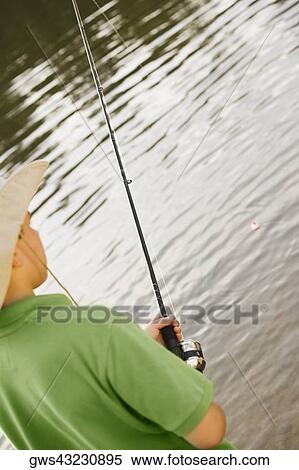 Rear view of a teenage boy holding a fishing rod View Large Photo Image Stock Photography - Rear view of a teenage boy holding a fishing rod. Fotosearch