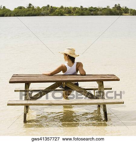 Rear view of a teenage girl sitting on a bench at a lakeside View Large Photo Image Stock Photo - Rear view of a teenage girl sitting on a bench at a lakeside. Fotosearch