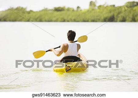 Rear view of a young man kayaking in a lake View Large Photo Image Stock Image - Rear view of a young man kayaking in a lake. Fotosearch