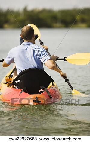 Rear view of a young man kayaking in a lake View Large Photo Image Stock Photo - Rear view of a young man kayaking in a lake. Fotosearch
