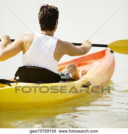 Stock Photography - Rear view of a young man kayaking in a lake. Fotosearch