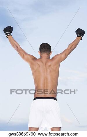 Rear view of a young man standing with his arms raised View Large Photo Image Stock Image - Rear view of a young man standing with his arms raised. Fotosearch