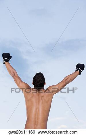 Rear view of a young man standing with his arms raised View Large Photo Image Stock Photo - Rear view of a young man standing with his arms raised. Fotosearch
