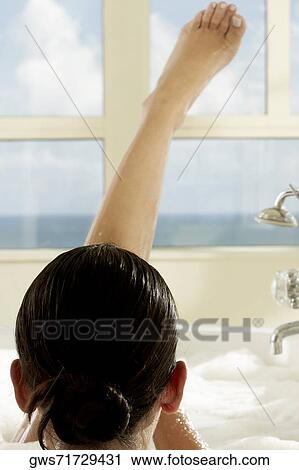 Rear view of a young woman in a bathtub with her leg raised View Large Photo Image Stock Image - Rear view of a young woman in a bathtub with her leg raised. Fotosearch