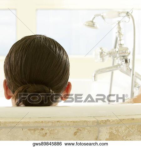 Stock Photograph - Rear view of a young woman in a bathtub. Fotosearch