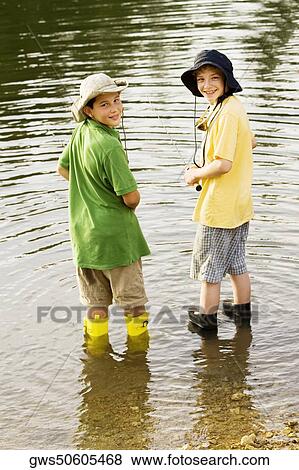 Rear view of two brothers fishing near a lake View Large Photo Image Stock Photo - Rear view of two brothers fishing near a lake. Fotosearch