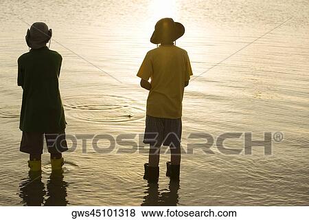 Rear view of two brothers standing in water View Large Photo Image Stock Photo - Rear view of two brothers standing in water. Fotosearch