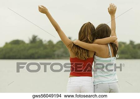 Rear view of two teenage girls with their arms around each other on the beach View Large Photo Image Picture - Rear view of two teenage girls with their arms around each other on the beach. Fotosearch