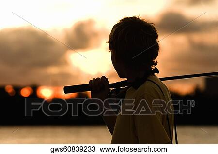 Stock Image - Side profile of a boy carrying a fishing rod. Fotosearch