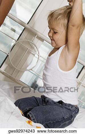 Stock Image - Side profile of a boy playing on the bed. Fotosearch