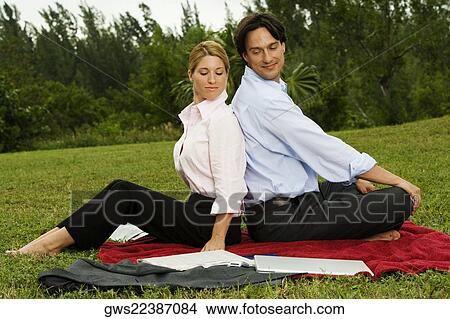 Side profile of a businessman and a businesswoman sitting back to back in the park View Large Photo Image Picture - Side profile of a businessman and a businesswoman sitting back to back in the park. Fotosearch