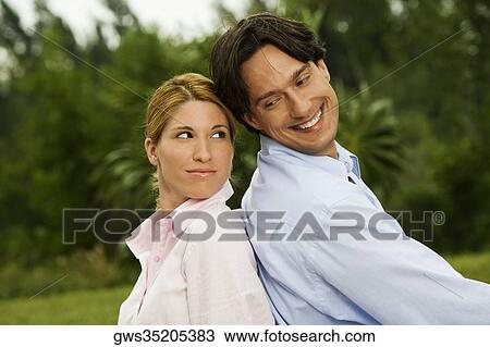 Side profile of a businessman and a businesswoman sitting back to back in the park View Large Photo Image Stock Image - Side profile of a businessman and a businesswoman sitting back to back in the park. Fotosearch