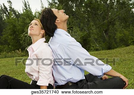 Side profile of a businessman and a businesswoman sitting back to back in the park View Large Photo Image Stock Image - Side profile of a businessman and a businesswoman sitting back to back in the park. Fotosearch
