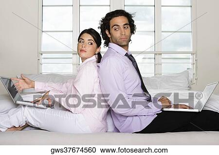 Side profile of a businessman and a businesswoman sitting back to back on the bed View Large Photo Image Stock Image - Side profile of a businessman and a businesswoman sitting back to back on the bed. Fotosearch