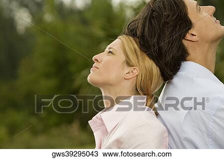Side profile of a businessman and a businesswoman sitting back to back in the park View Large Photo Image Stock Image - Side profile of a businessman and a businesswoman sitting back to back in the park. Fotosearch