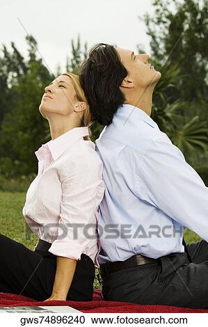 Side profile of a businessman and a businesswoman sitting back to back in the park View Large Photo Image Stock Image - Side profile of a businessman and a businesswoman sitting back to back in the park. Fotosearch