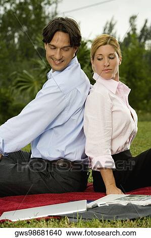 Side profile of a businessman and a businesswoman sitting back to back in the park View Large Photo Image Stock Image - Side profile of a businessman and a businesswoman sitting back to back in the park. Fotosearch
