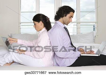 Side profile of a businessman and a businesswoman sitting back to back on the bed View Large Photo Image Stock Photo - Side profile of a businessman and a businesswoman sitting back to back on the bed. Fotosearch