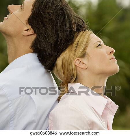 Side profile of a businessman and a businesswoman sitting back to back in the park View Large Photo Image Stock Photography - Side profile of a businessman and a businesswoman sitting back to back in the park. Fotosearch