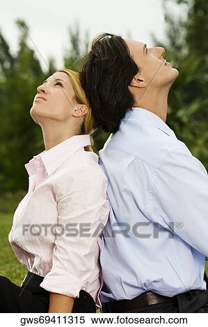 Side profile of a businessman and a businesswoman sitting back to back in the park View Large Photo Image Stock Photography - Side profile of a businessman and a businesswoman sitting back to back in the park. Fotosearch